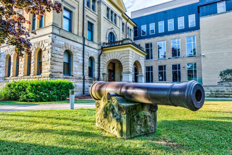 Historic cannon on the courthouse lawn beside the stone and brick facade.